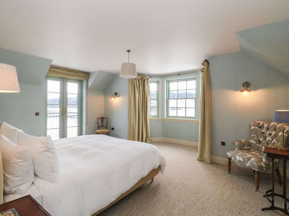 A bedroom with a bed and chair at Schiehallion House in Pitlochry