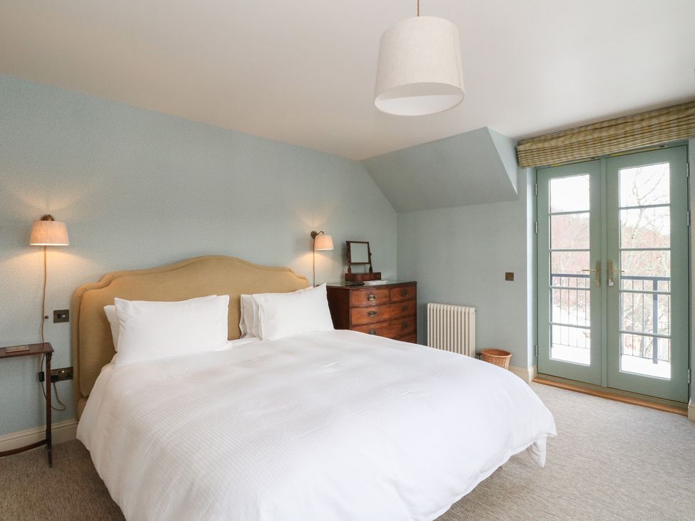A bedroom with a double bed and wooden furniture at Schiehallion House in Pitlochry