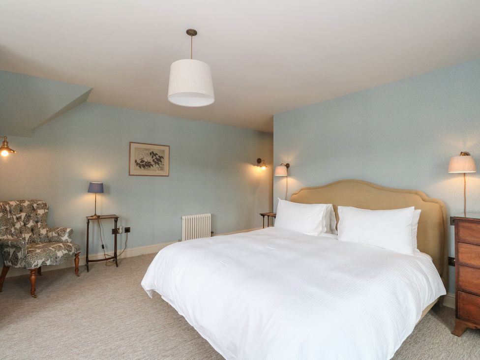 A bedroom with a bed and chair at Schiehallion House in Pitlochry