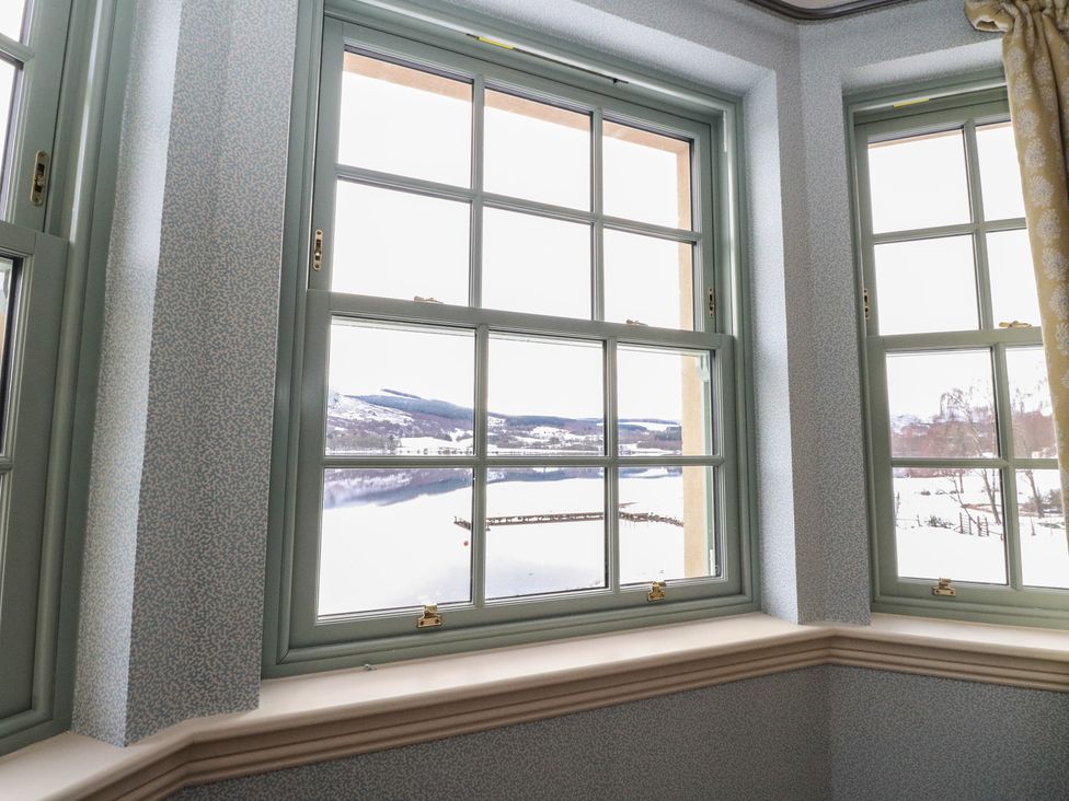 A living room with windows overlooking a lake at Schiehallion House in Pitlochry