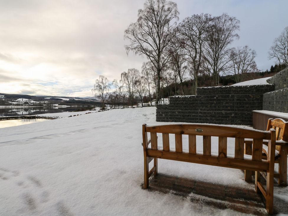A bench in the snow near a river at Schiehallion House in Pitlochry