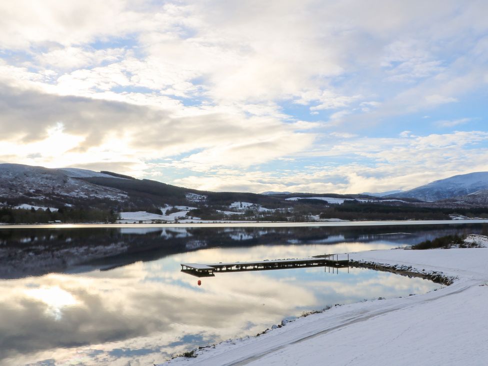 A scenic view of a lake with a pier and snow at Schiehallion House in Pitlochry
