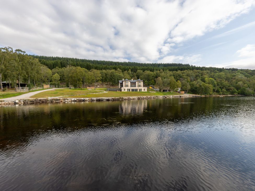 A house by a river with trees and a pathway at Schiehallion House Pitlochry