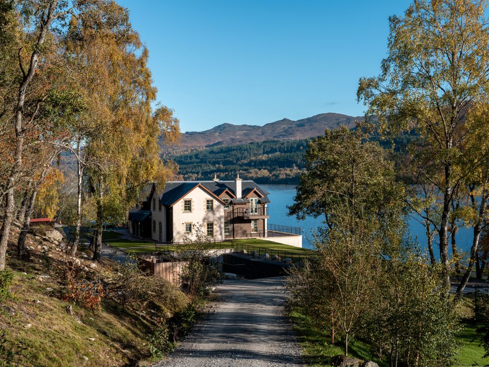 A house near a lake with a road and trees at Schiehallion House in Pitlochry
