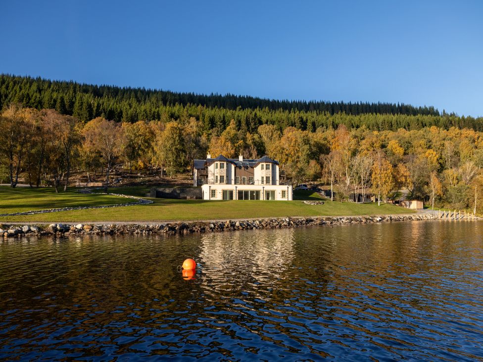 A house next to a lake with trees in the background at Schiehallion House in Pitlochry