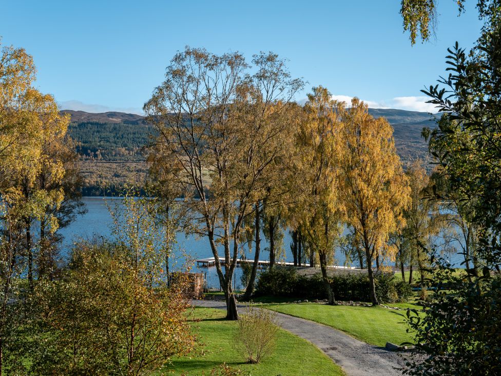 A view of a lake with trees and a pathway at Schiehallion House in Pitlochry