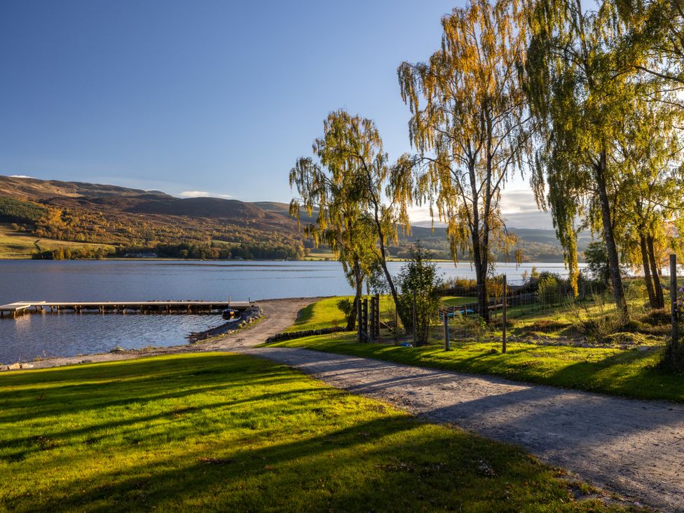 A lakeside view with trees and a path at Schiehallion House in Pitlochry