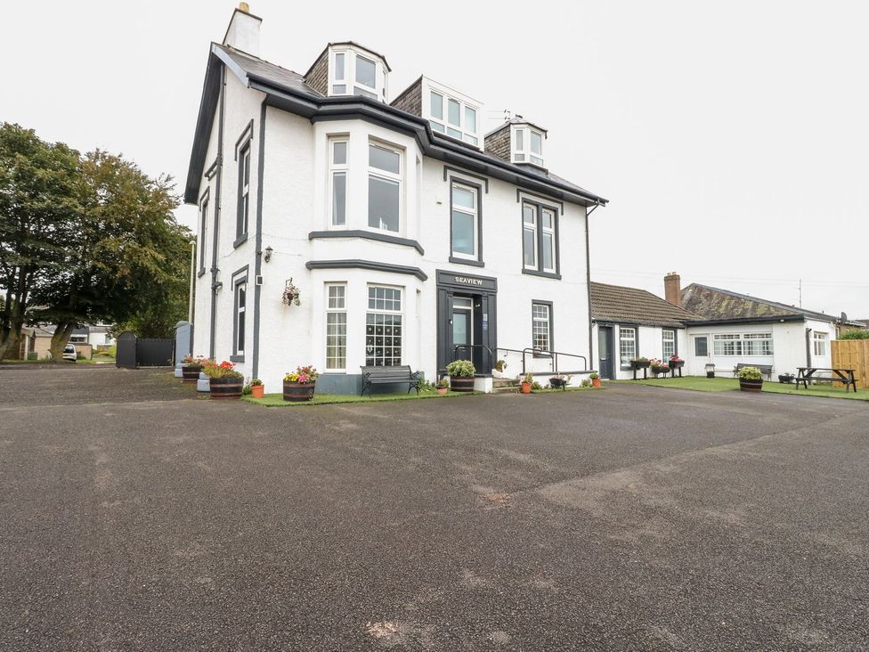 A view of a large building with planters and a parking lot at Seaview Wellness Retreat in Carnoustie