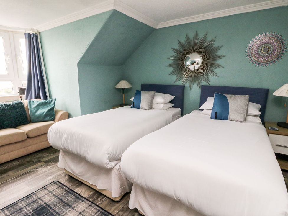 A bedroom with twin beds and a sofa at Seaview Wellness Retreat in Carnoustie
