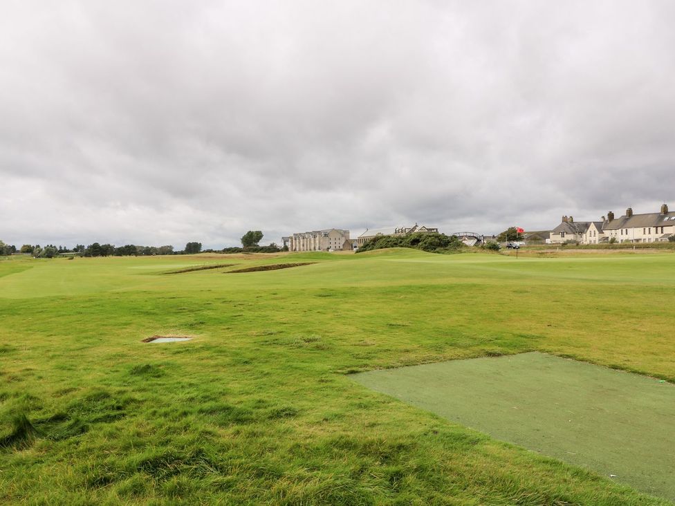 A golf course with grass and houses at Seaview Wellness Retreat in Carnoustie