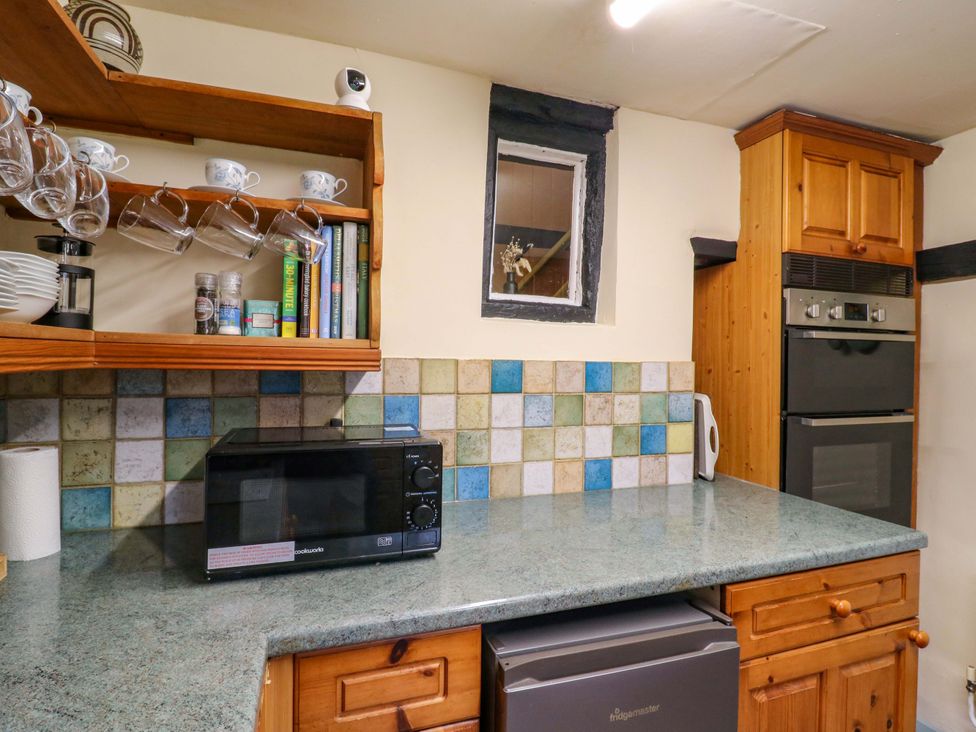 A kitchen with a microwave, shelves, and oven at 118 High Street, Bedford