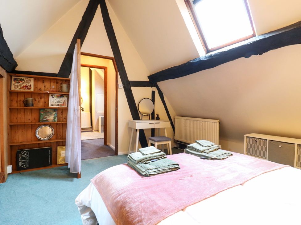 A bedroom with a bed, towels, and a shelf at 118 High Street, Bedford