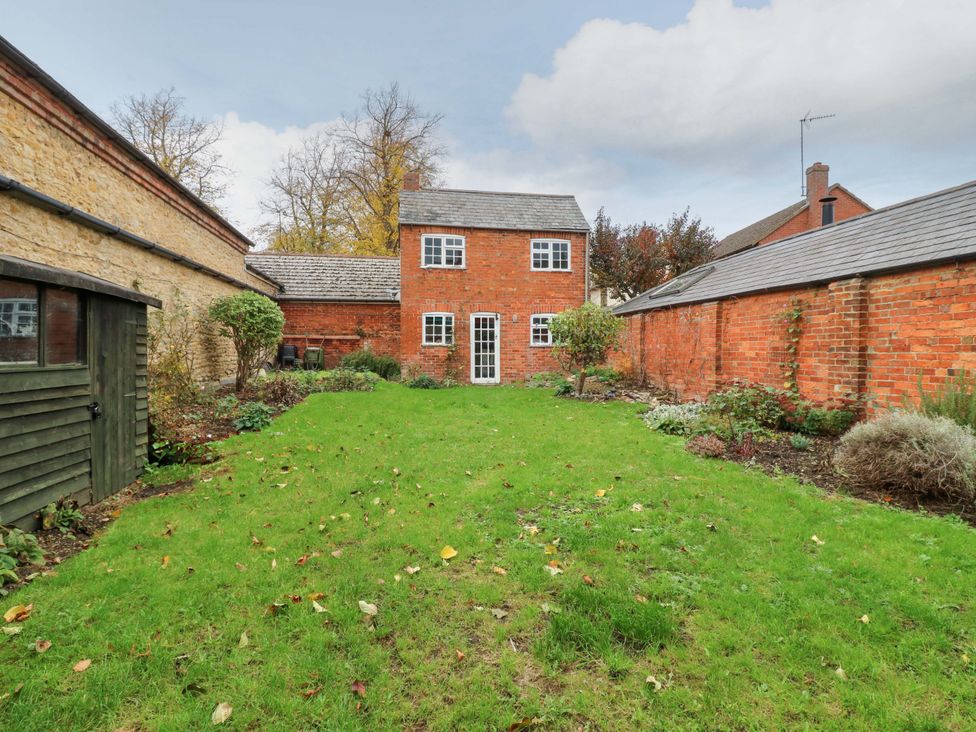 A garden with a brick house and shed at 118 High Street Bedford