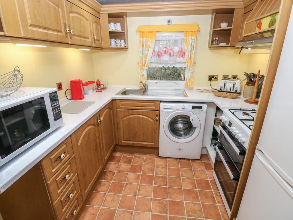 A kitchen with cabinets, a washing machine, and a microwave at Static Caravan