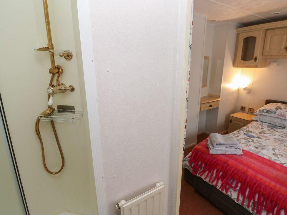 A bathroom with a shower and bed at Static Caravan