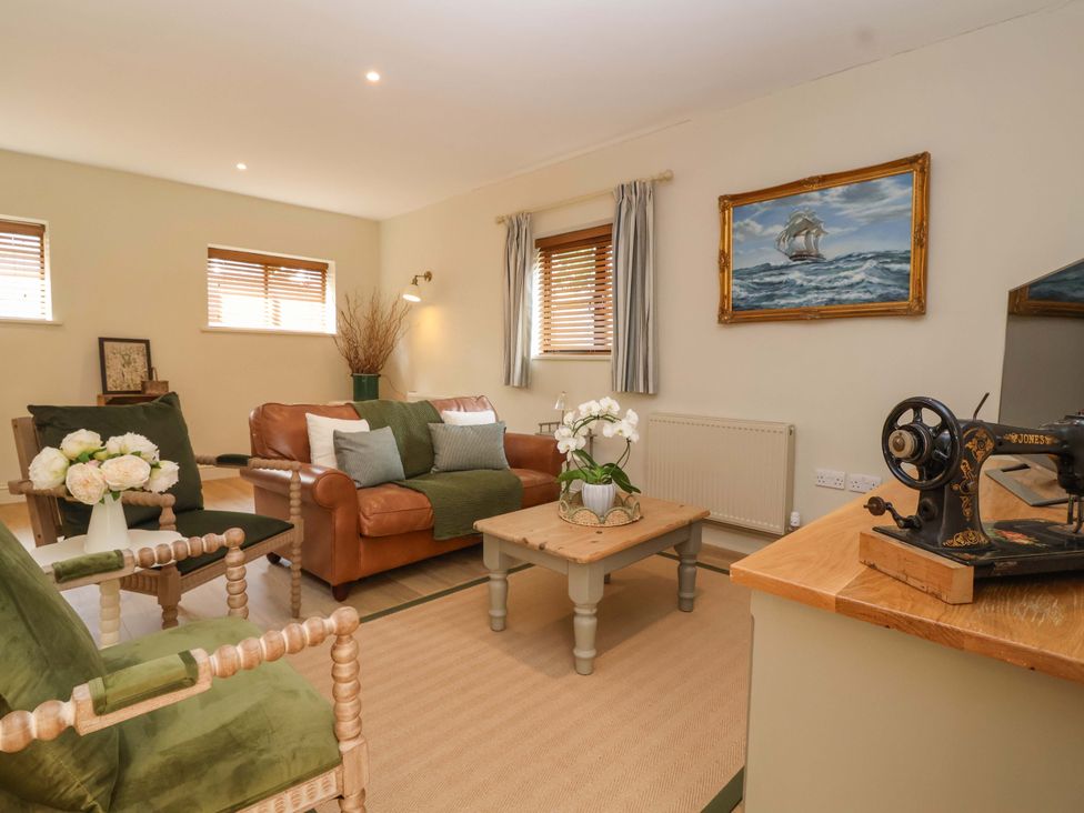 A living room with a sofa, armchairs, and a table at The Annex in Burford