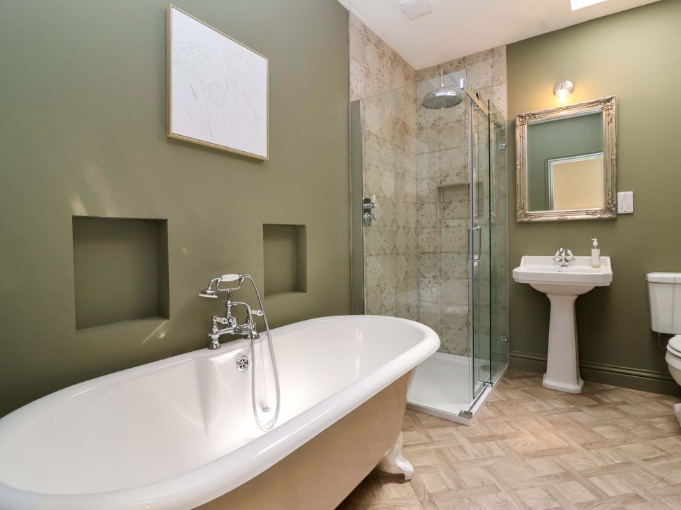 A bathroom with a bathtub, shower, sink, and toilet at The Annex in Burford