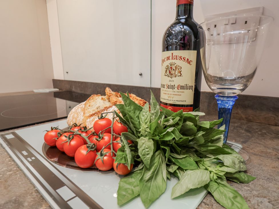 A kitchen counter with wine, glass, bread, tomatoes, and basil at 1 Castle Terrace Thirsk