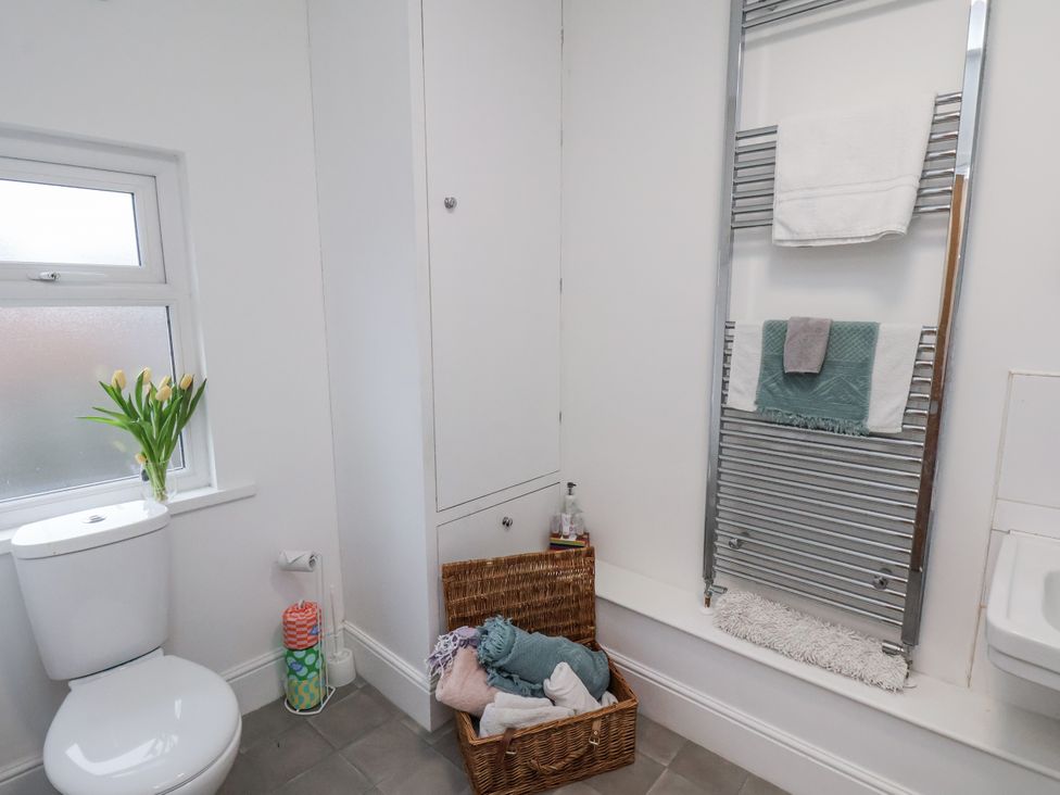 A bathroom with a toilet, towel rack and basket at 1 Castle Terrace in Thirsk