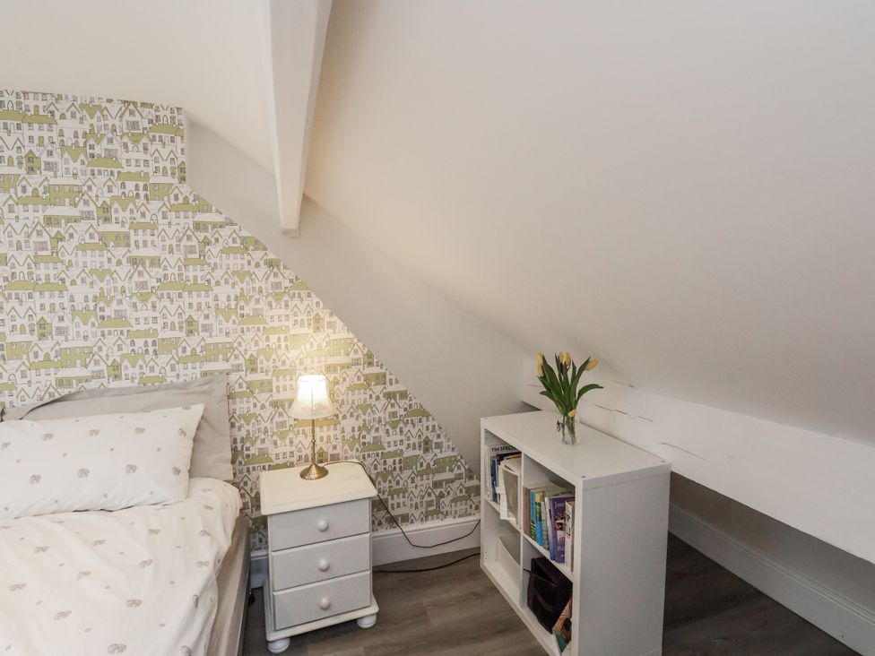 A bedroom with a bed, nightstand, lamp, and bookshelf at 1 Castle Terrace in Thirsk