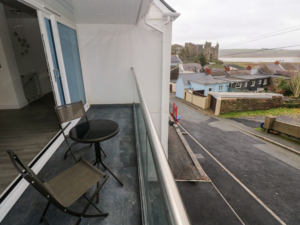 A balcony with a table and chairs overlooking a road at Cottage 1 in Laugharne