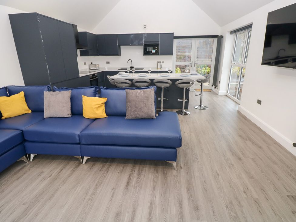 A living room with blue sofa and kitchen area at Cottage 1 in Laugharne