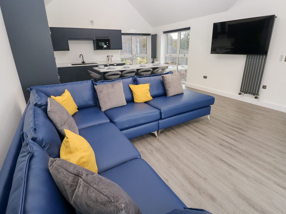 A living room with a sofa and kitchen area at Cottage 1 in Laugharne