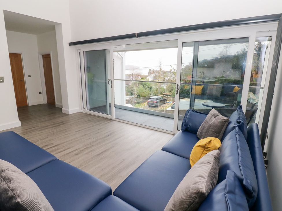 A living room with a sofa and doors to a balcony at Cottage 1 in Laugharne