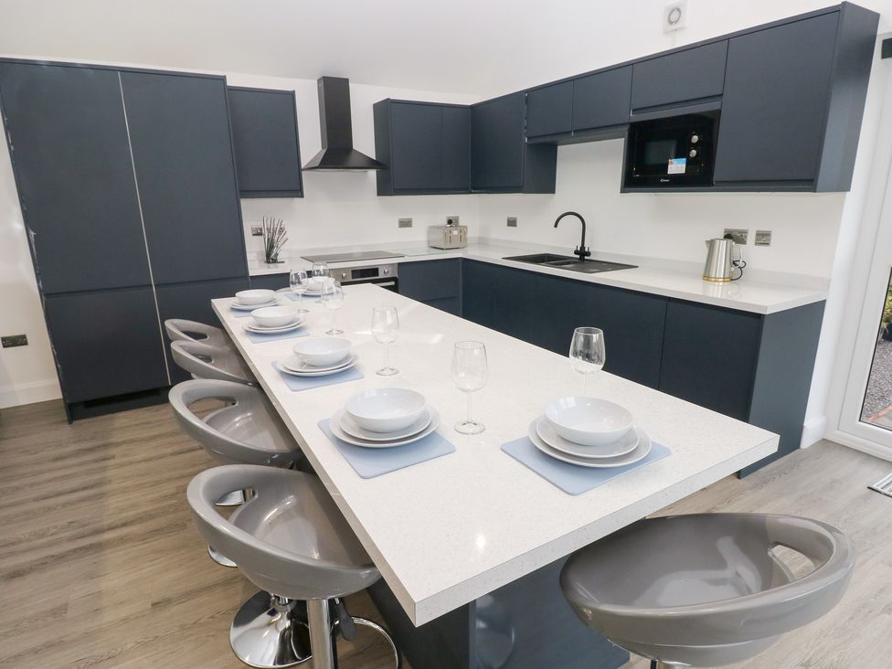 A kitchen with bar stools and dishware at Cottage 1 in Laugharne