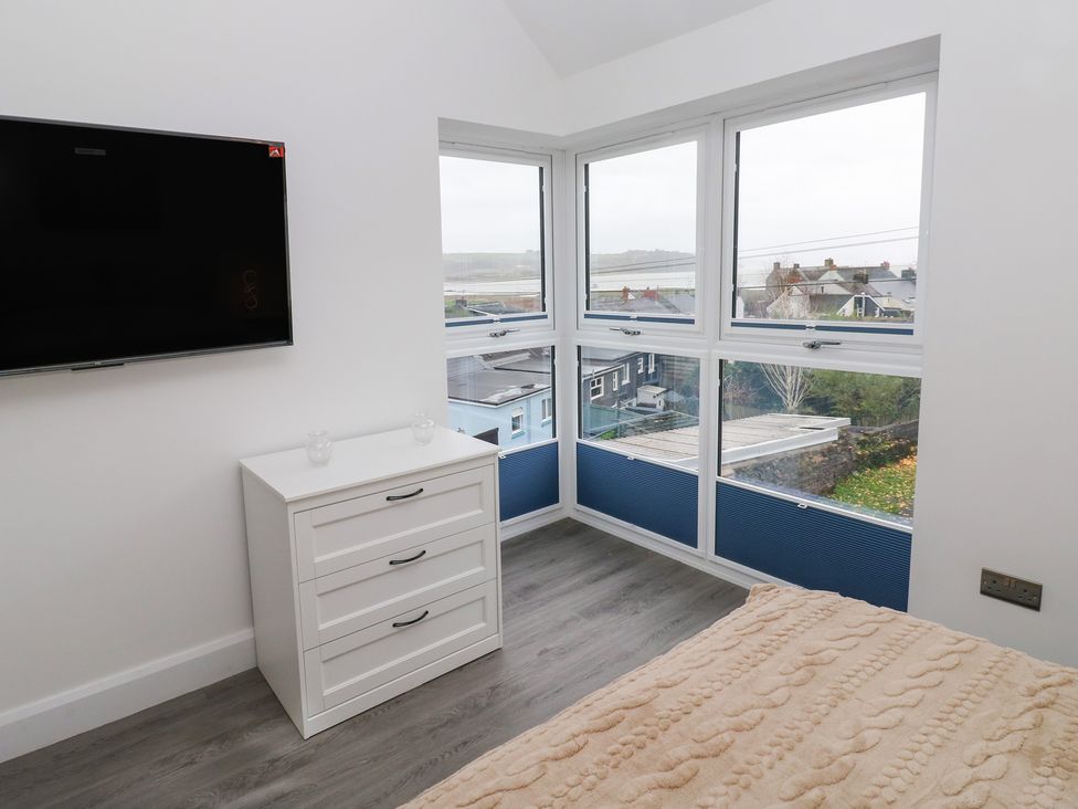A bedroom with a television, a chest of drawers, and a bed at Cottage 1 in Laugharne