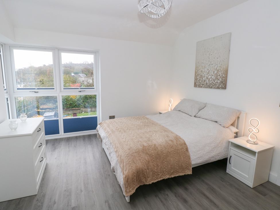 A bedroom with a bed and nightstand at Cottage 1 in Laugharne