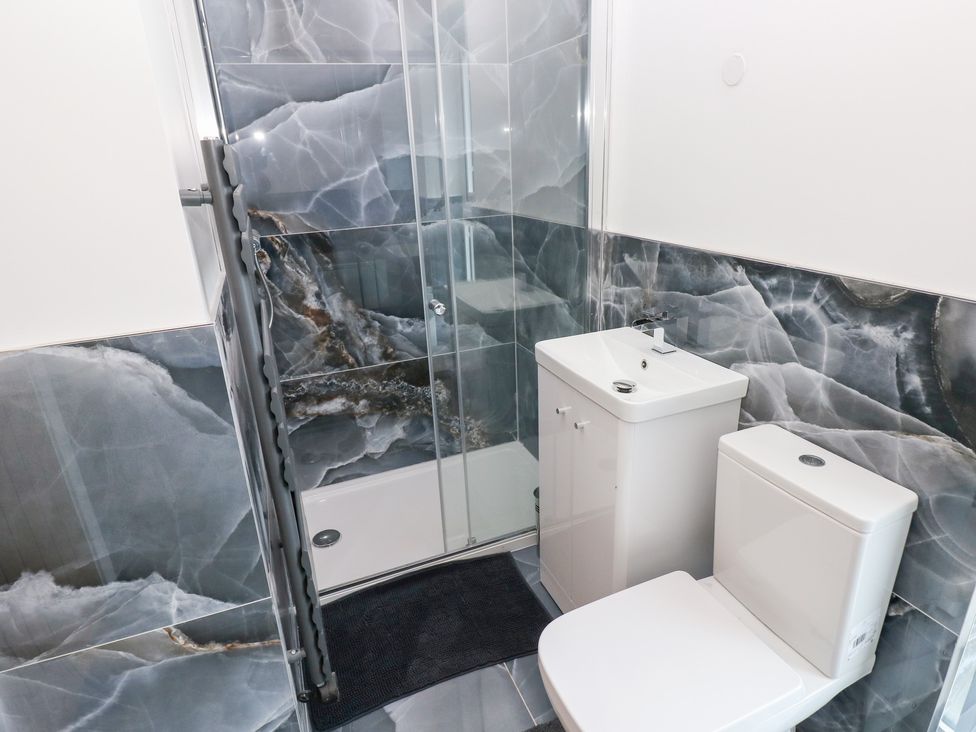A bathroom with a shower, toilet, and sink at Cottage 1 in Laugharne
