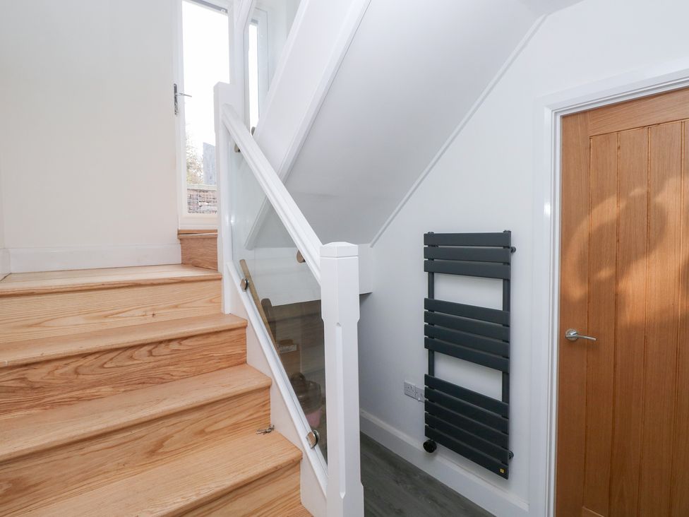 A hallway with stairs and a heated towel rail at Cottage 1 in Laugharne