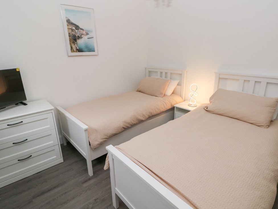 A bedroom with two single beds and a television at Cottage 1 in Laugharne