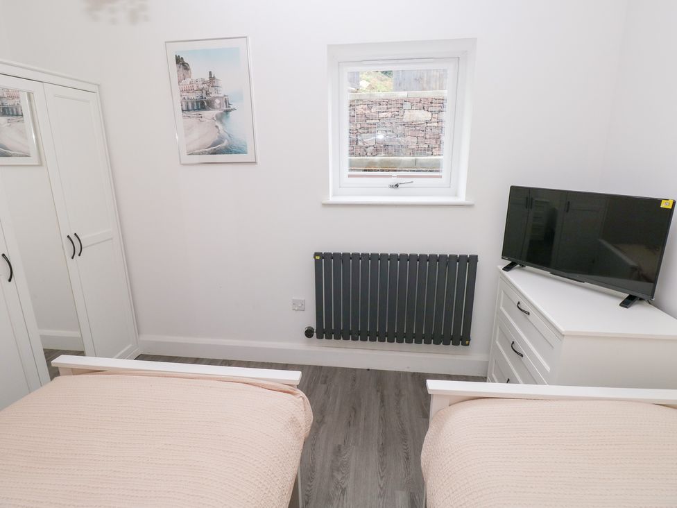 A bedroom with two beds and a television at Cottage 1 in Laugharne