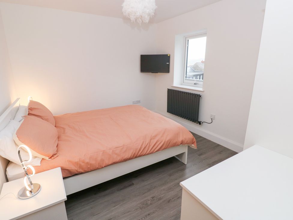 A bedroom with a bed, television and window at Cottage 1 in Laugharne
