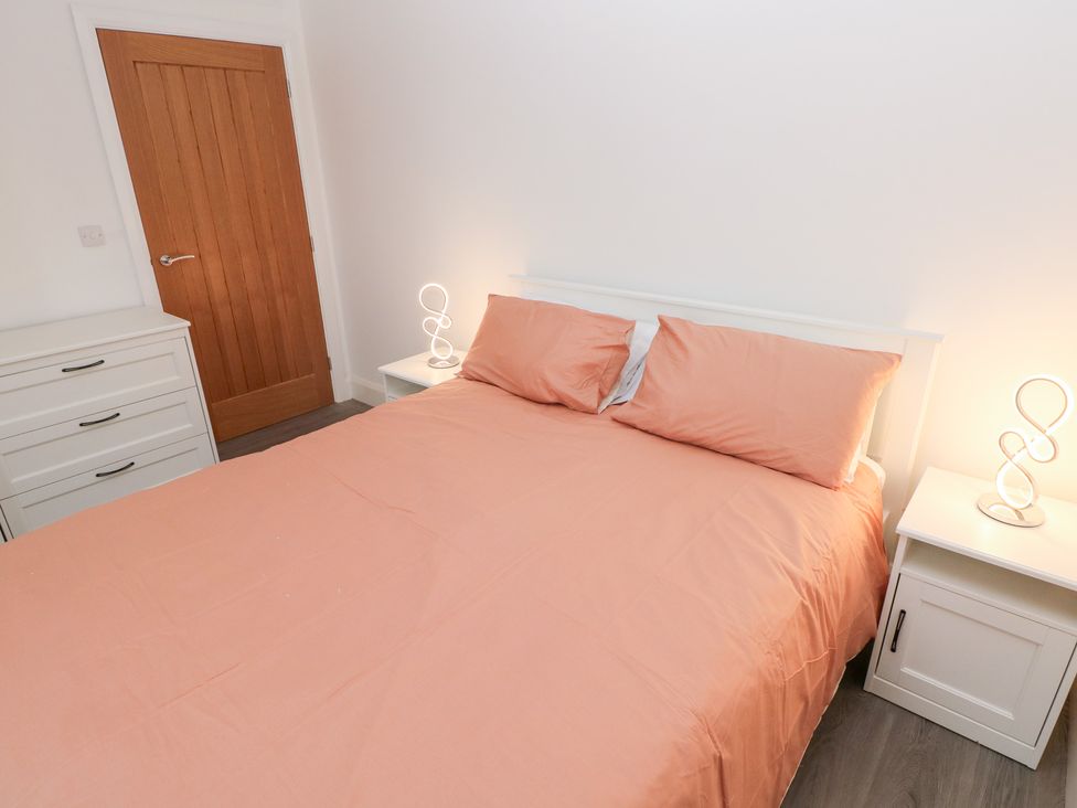 A bedroom with a bed and nightstands at Cottage 1 in Laugharne