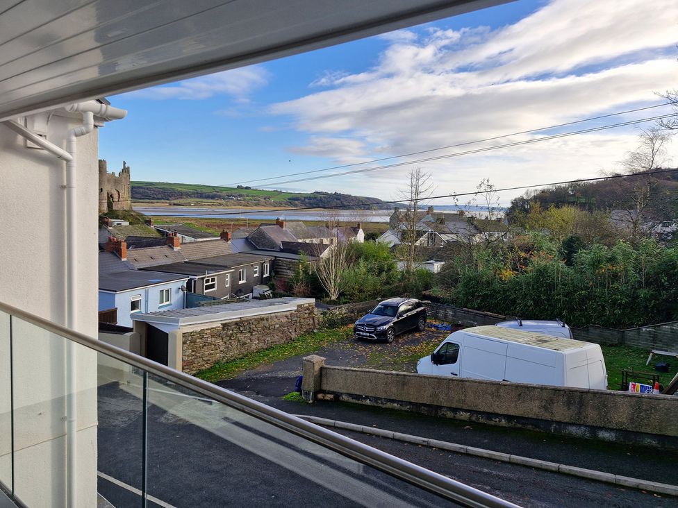 A view of houses and cars with a castle in the background at Milkwood Villa Laugharne