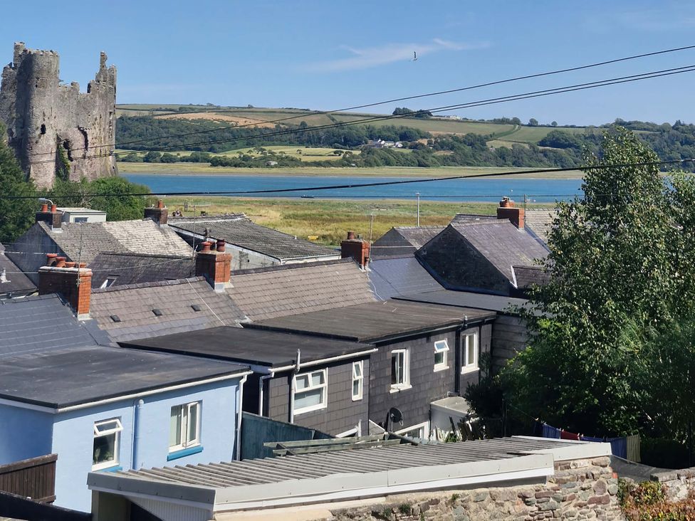 A view of rooftops, a castle and water at Milkwood Villa in Laugharne
