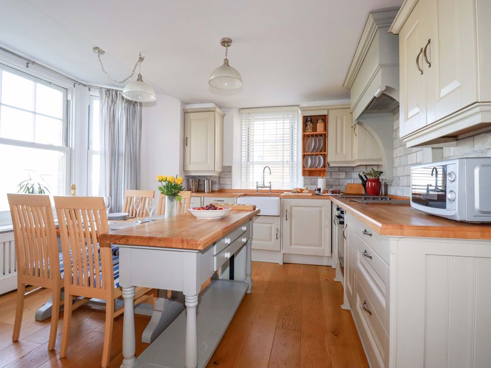 A kitchen with cabinets and a central table at Tradewinds in Newquay