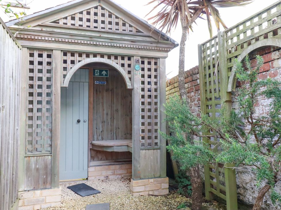 A garden structure with wooden door and decorative lattice at Tradewinds in Newquay
