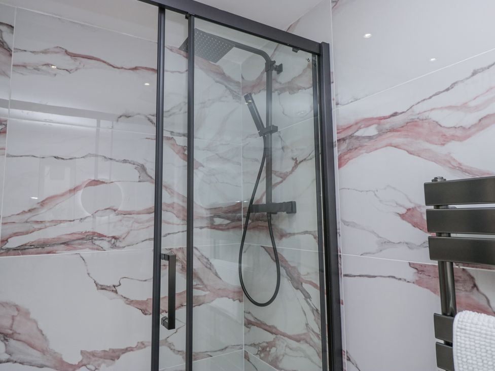 A bathroom with a glass shower and marble wall tiles at Aspen Boutique