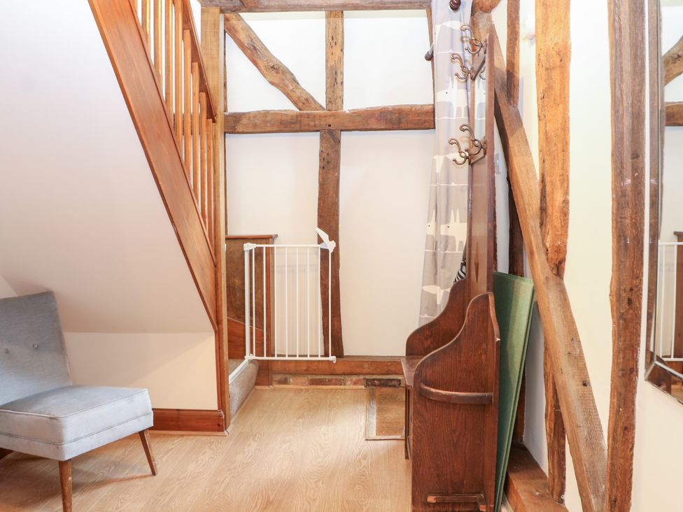 A hallway with a staircase and a chair at WEST LODGE in Ashford