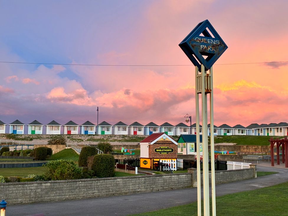A park area with beach huts and sign at Queens Park in Mablethorpe