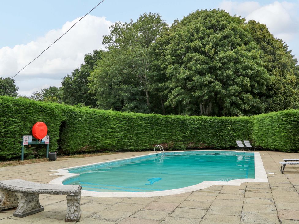 An outdoor swimming pool with chairs and a lifebuoy at Daisy Cottage Pevensey
