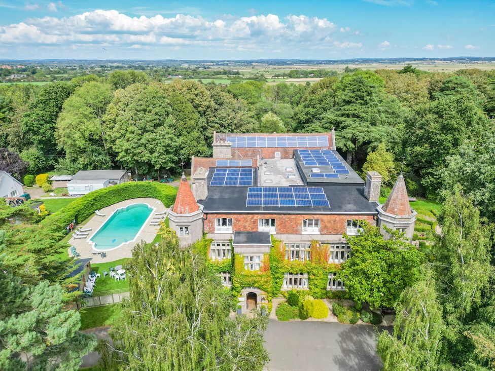 An aerial view of a house with a swimming pool and solar panels at Daisy Cottage in Stone Cross
