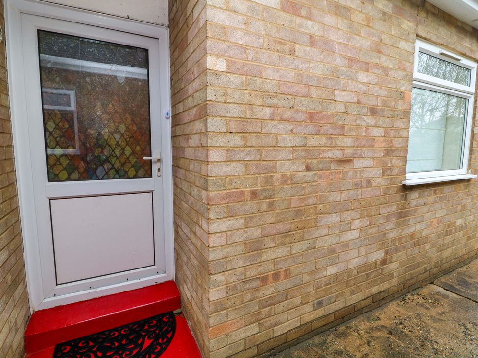 An entrance with a door and window next to a brick wall at 5 Overstone Drive Wisbech