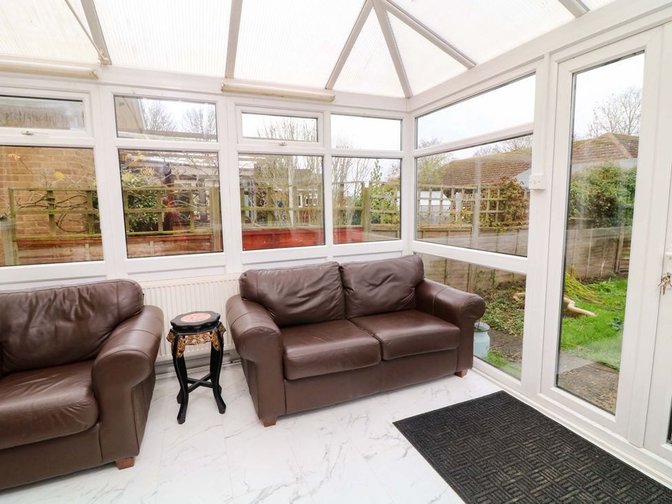 A conservatory with two leather sofas and a small table at 5 Overstone Drive, Wisbech