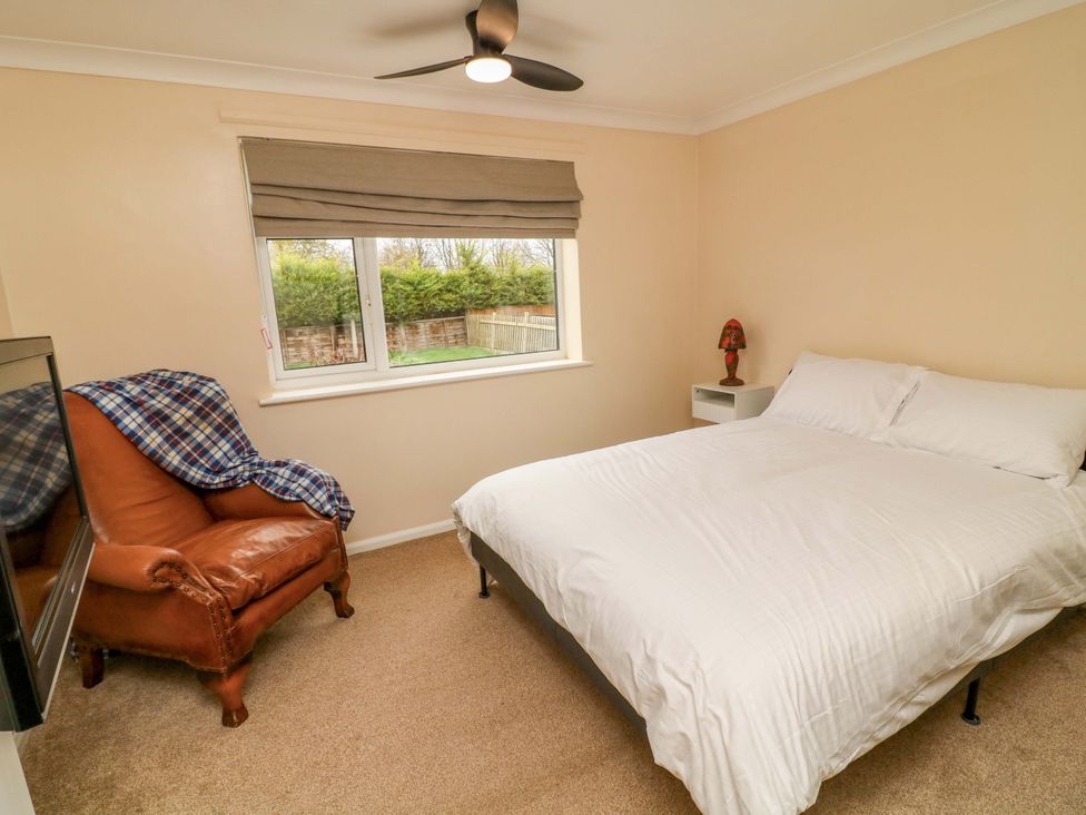 A bedroom with a bed and an armchair at 5 Overstone Drive in Wisbech