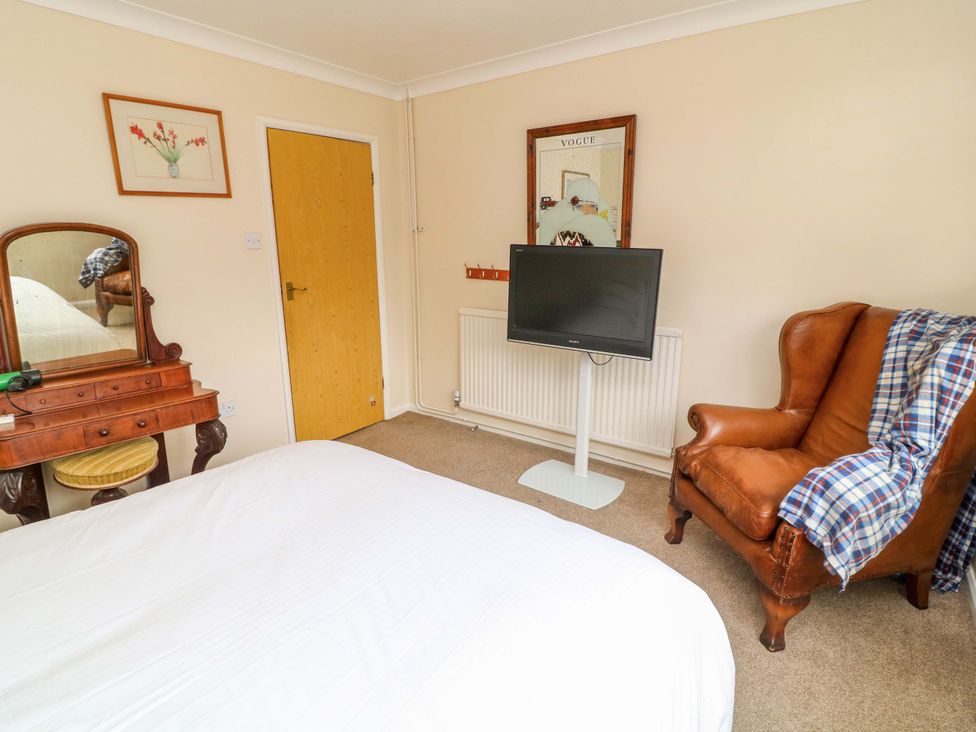 A bedroom with a bed, table, chair, and television at 5 Overstone Drive Wisbech